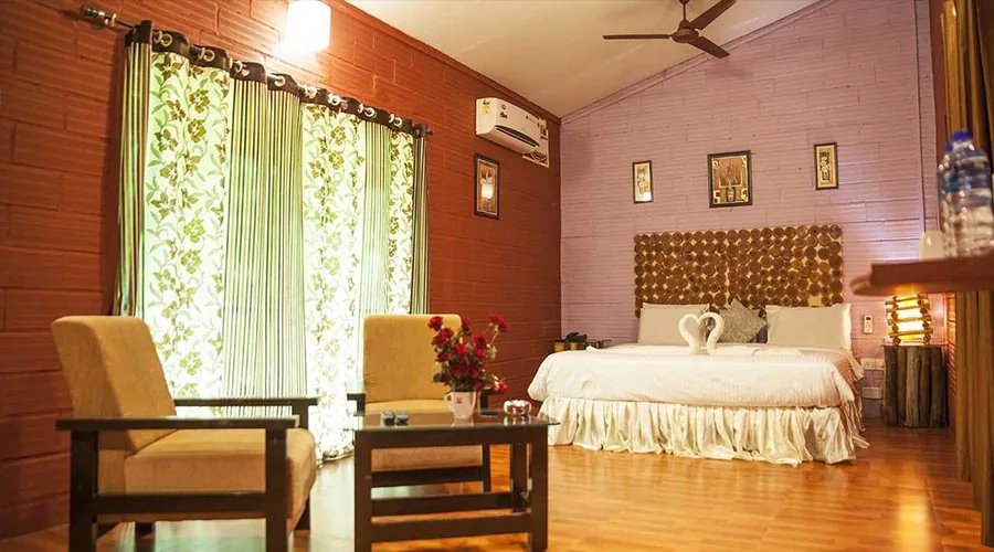Cottage bedroom with brick walls and seating at Century Resort Dandeli
