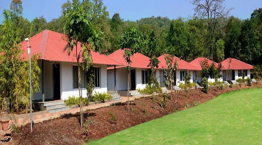 Row of white cottages with red roofs at Whistling Woods Dandeli