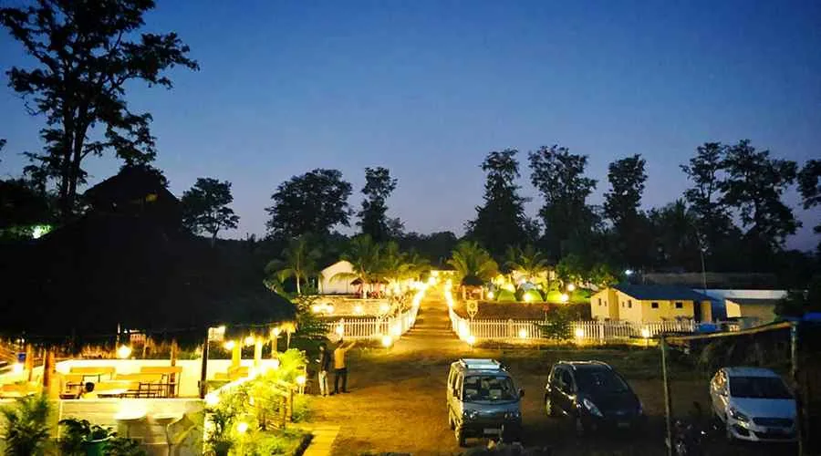 Evening path with lit dining pavilion at Jungle Bell River Resort Dandeli