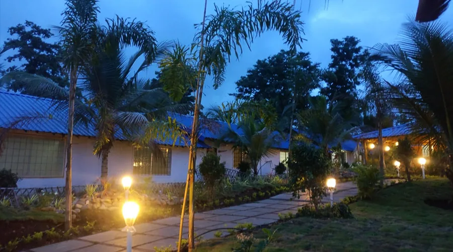 Blue-roof cottages at twilight at Jungle Bell River Resort Dandeli