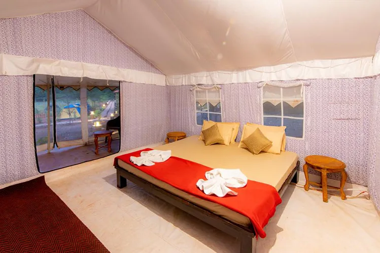 Interior of a luxury tent with wooden bed at Tusker Trails Dandeli
